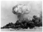 １９４２年２月１９日、ダーウィン。日本軍の最初の空襲によって爆発したオイルタンク。発火したタンクから流れる濃い黒煙を縫って火の玉が吹き上がっている。停泊中のバサースト級コルベット艦「デロレイン」が前景に小さく見えることからも爆発の規模の大きさが窺える。オーストラリア本土に対する日本軍の攻撃は、遠方のヨーロッパの敵ドイツとイタリアからは決して受けることのない脅威となってオーストラリア国民を不安に陥れた。１９４２年の年間を通じてオーストラリア人は日本の侵略を本当に恐れていた。