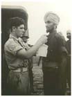 Hari Singh has a hospital tag pinned on him by an Australian medical orderly before boarding a waiting ambulance for evacuation to Australia, 12 May 1944.  Hari Singh was one of sixty-nine Sikh soldiers liberated by American troops on Los Negros in the Admiralty Islands two months earlier.  These were the first Indian prisoners of war to be liberated in New Guinea and their presence came as a complete surprise to the advancing Allied forces.