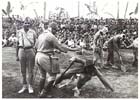 Dressed up as a Japanese officer, Havildar Bostan Khan, with the help of fellow ex-prisoners, demonstrates some of the routine cruelties visited upon the Indians by their captors during a visit by the 11th Australian Division’s commander, Major General K. W. Eather, Karavia Bay, New Britain, 23 October 1945.  Role-playing like this helped the Indians to overcome language difficulties in explaining to their Australian liberators just what had happened to them as prisoners of the Japanese.