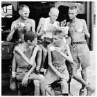 Five Australian former prisoners of war catch up on news from home after their release from Japanese captivity in Singapore, September 1945.  The brutal treatment inflicted upon these men by their Japanese captors is clearly illustrated by their poor physical condition. 